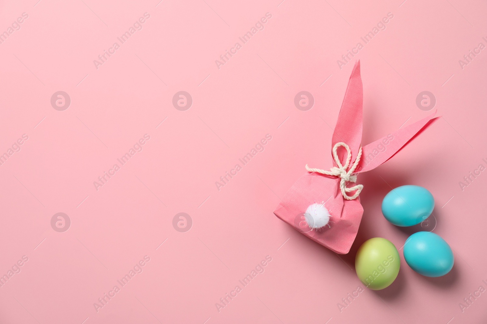 Photo of Flat lay composition of Easter bunny gift bag and dyed eggs on color background. Space for text