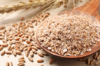 Photo of Wheat bran and kernels on wooden table, closeup