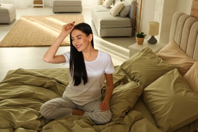 Photo of Young woman on bed with green linens at home
