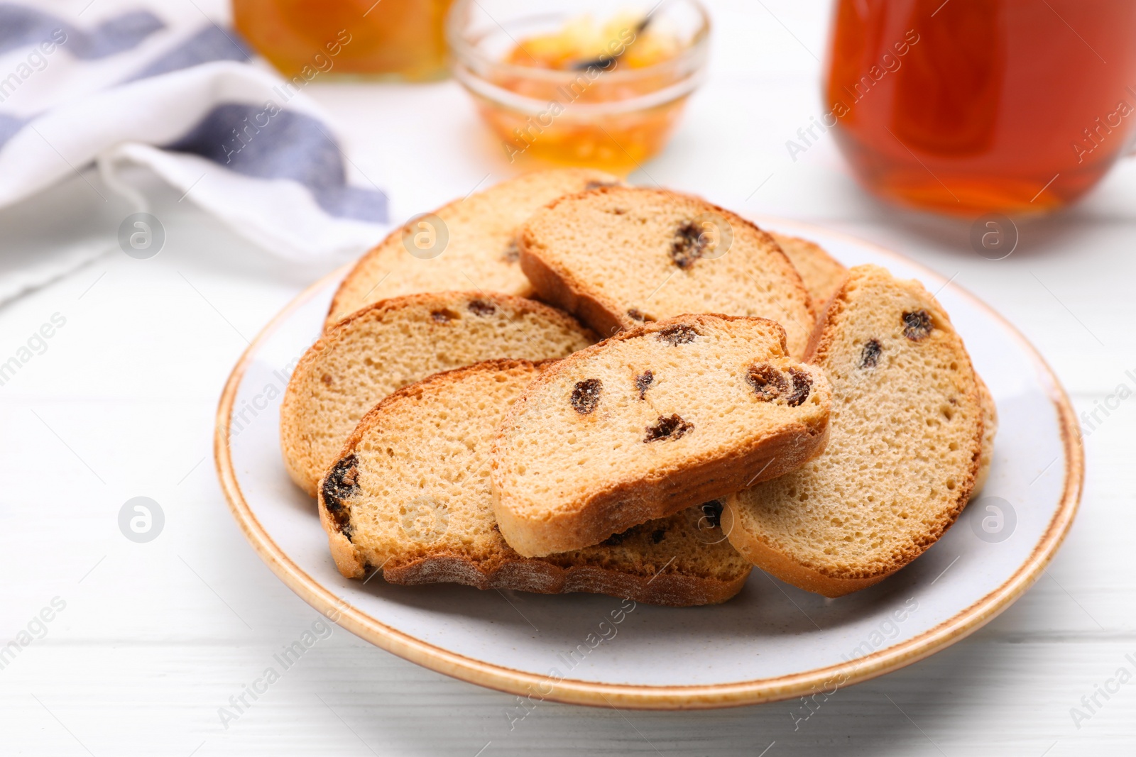 Photo of Plate of sweet hard chuck crackers with raisins on white wooden table