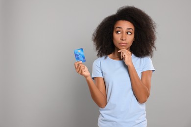 Photo of Woman with credit card on grey background, space for text. Debt problem