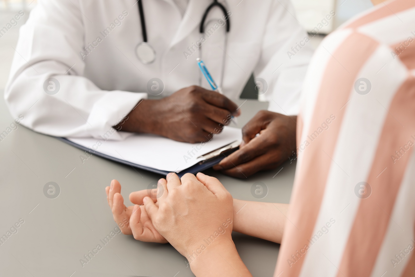 Photo of Young African-American doctor consulting patient in hospital