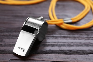 One metal whistle with cord on wooden table, closeup