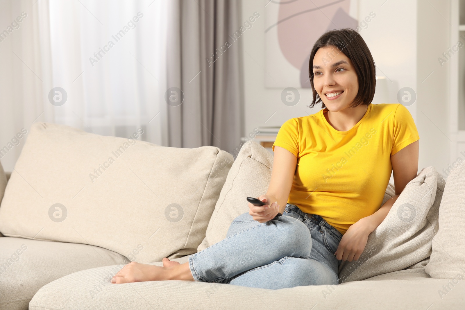 Photo of Happy woman watching TV on sofa indoors, space for text