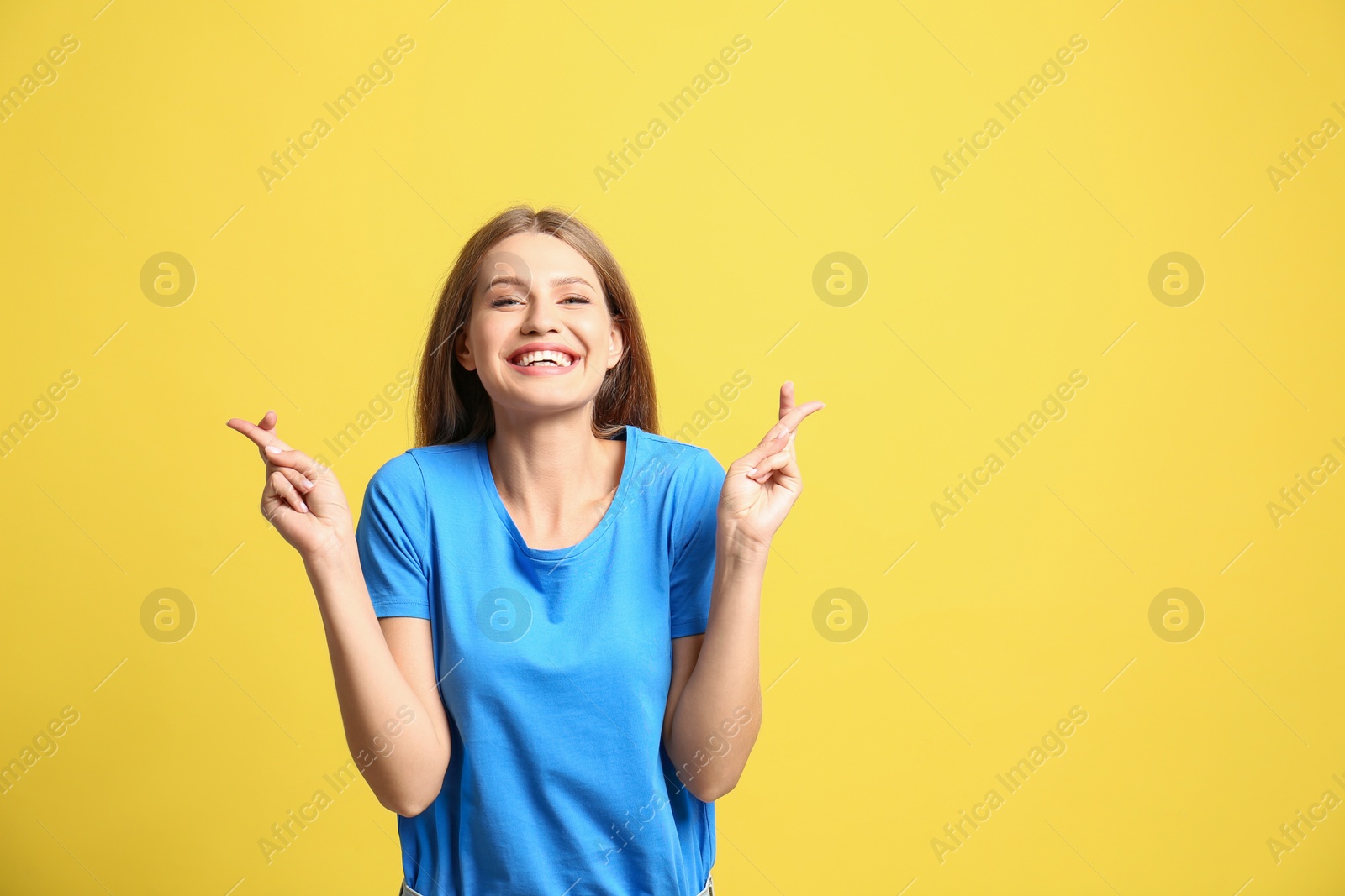 Photo of Portrait of hopeful woman with crossed fingers on yellow background