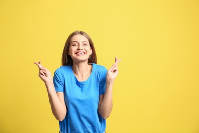 Photo of Portrait of hopeful woman with crossed fingers on yellow background