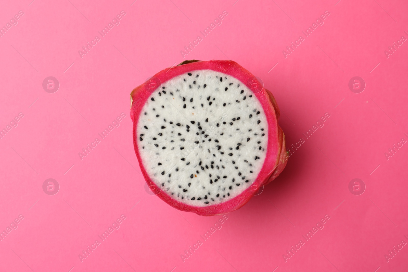 Photo of Half of delicious ripe dragon fruit (pitahaya) on pink background, top view