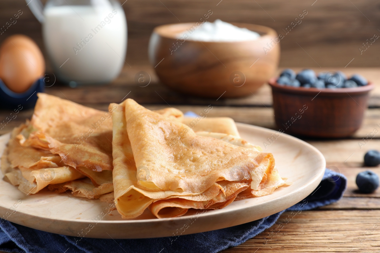 Photo of Delicious crepes served on wooden table, closeup. Space for text