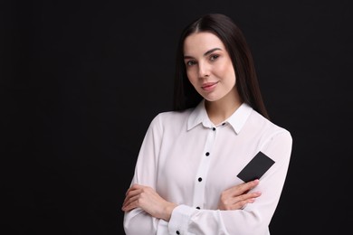 Woman holding blank business card on black background. Space for text