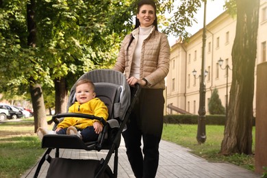 Happy mother walking with her son in stroller outdoors