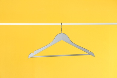 Photo of Metal rack with clothes hanger on color background