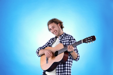 Young man playing acoustic guitar on color background