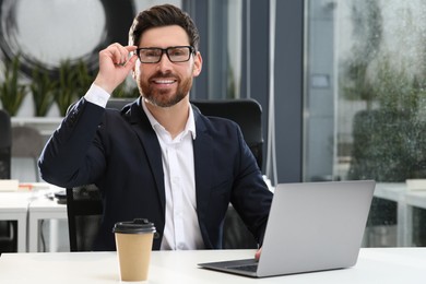 Man working on laptop at white desk in office