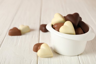 Photo of Beautiful heart shaped chocolate candies on white wooden table, space for text
