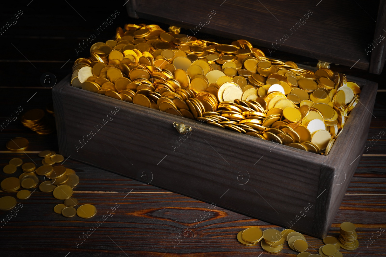 Image of Open treasure chest with gold coins on wooden table