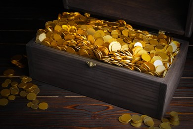 Open treasure chest with gold coins on wooden table