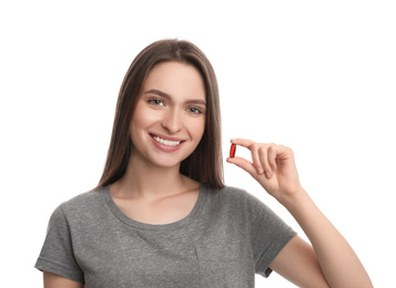 Young woman with vitamin pill on white background