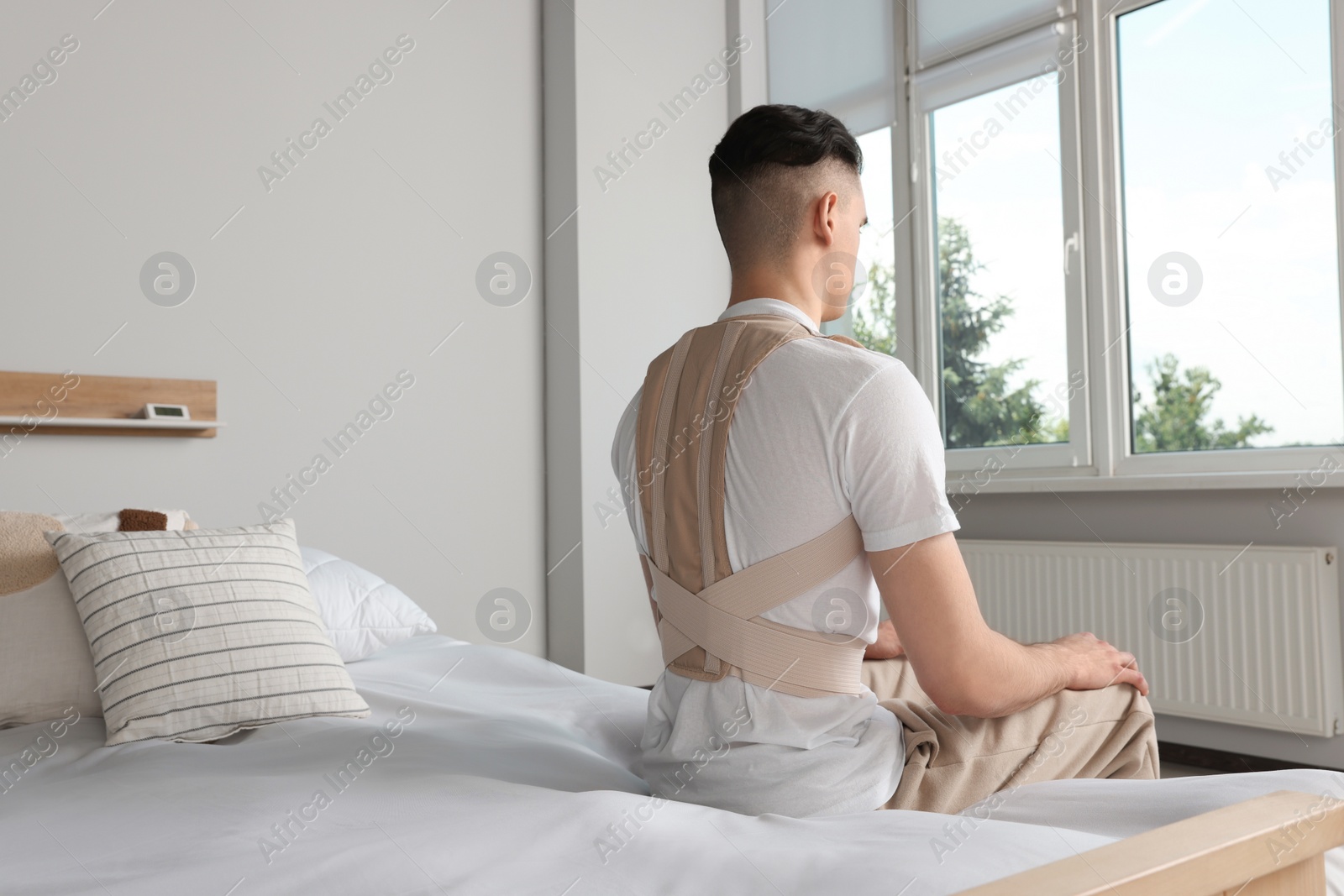 Photo of Man with orthopedic corset sitting in bedroom