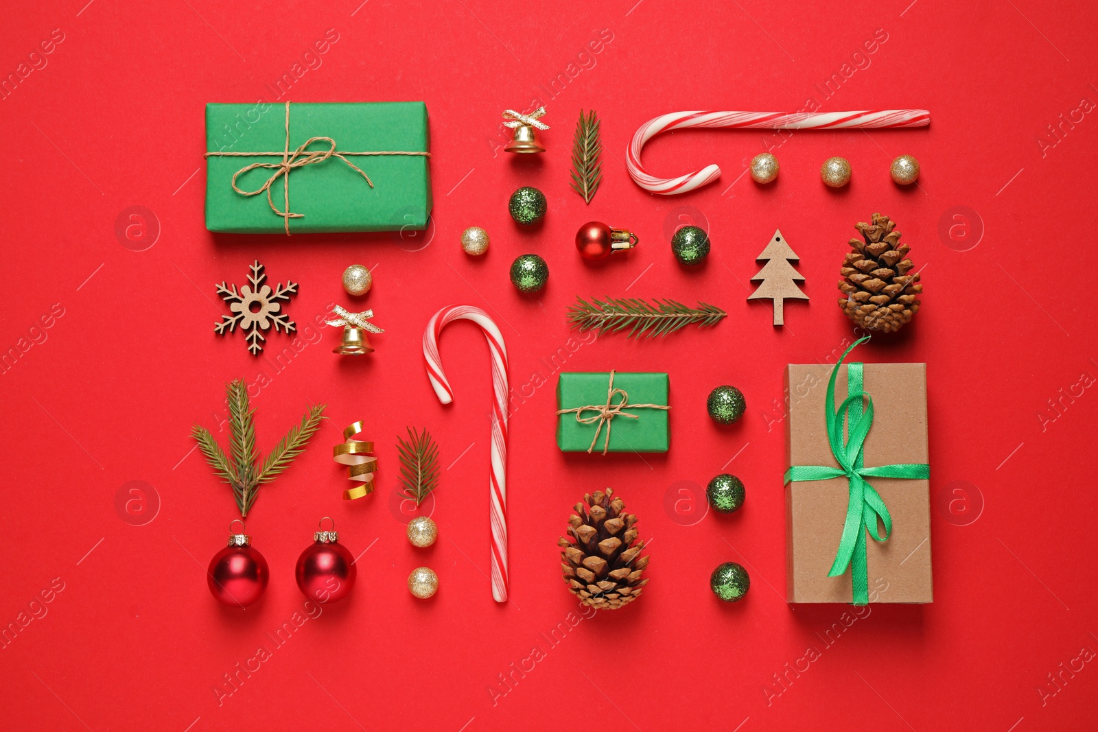 Photo of Christmas tree branches and festive decoration on red background, flat lay