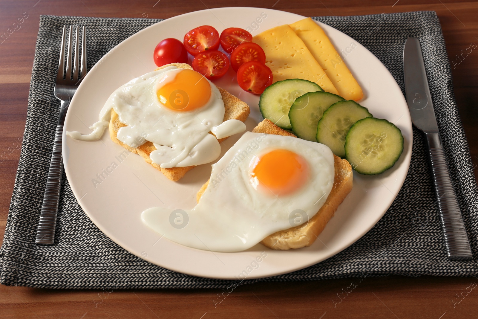 Photo of Tasty toasts with fried eggs, cheese and vegetables on wooden table