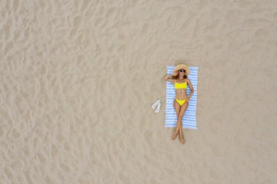 Woman sunbathing on beach towel at sandy coast, aerial view. Space for text