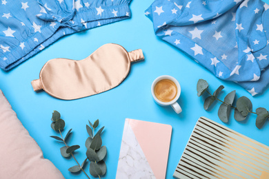 Flat lay composition with sleeping mask on light blue background. Bedtime accessories