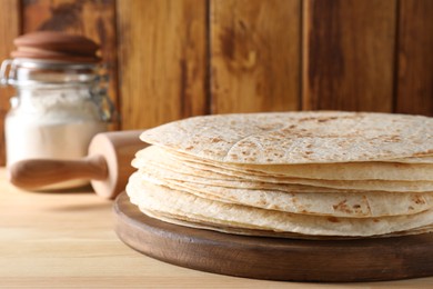 Photo of Many tasty homemade tortillas on wooden table, closeup