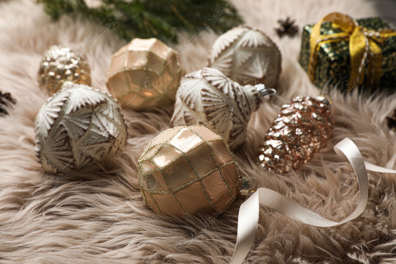 Photo of Composition with beautiful Christmas baubles on beige fur, closeup
