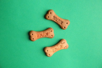 Bone shaped dog cookies on green background, flat lay