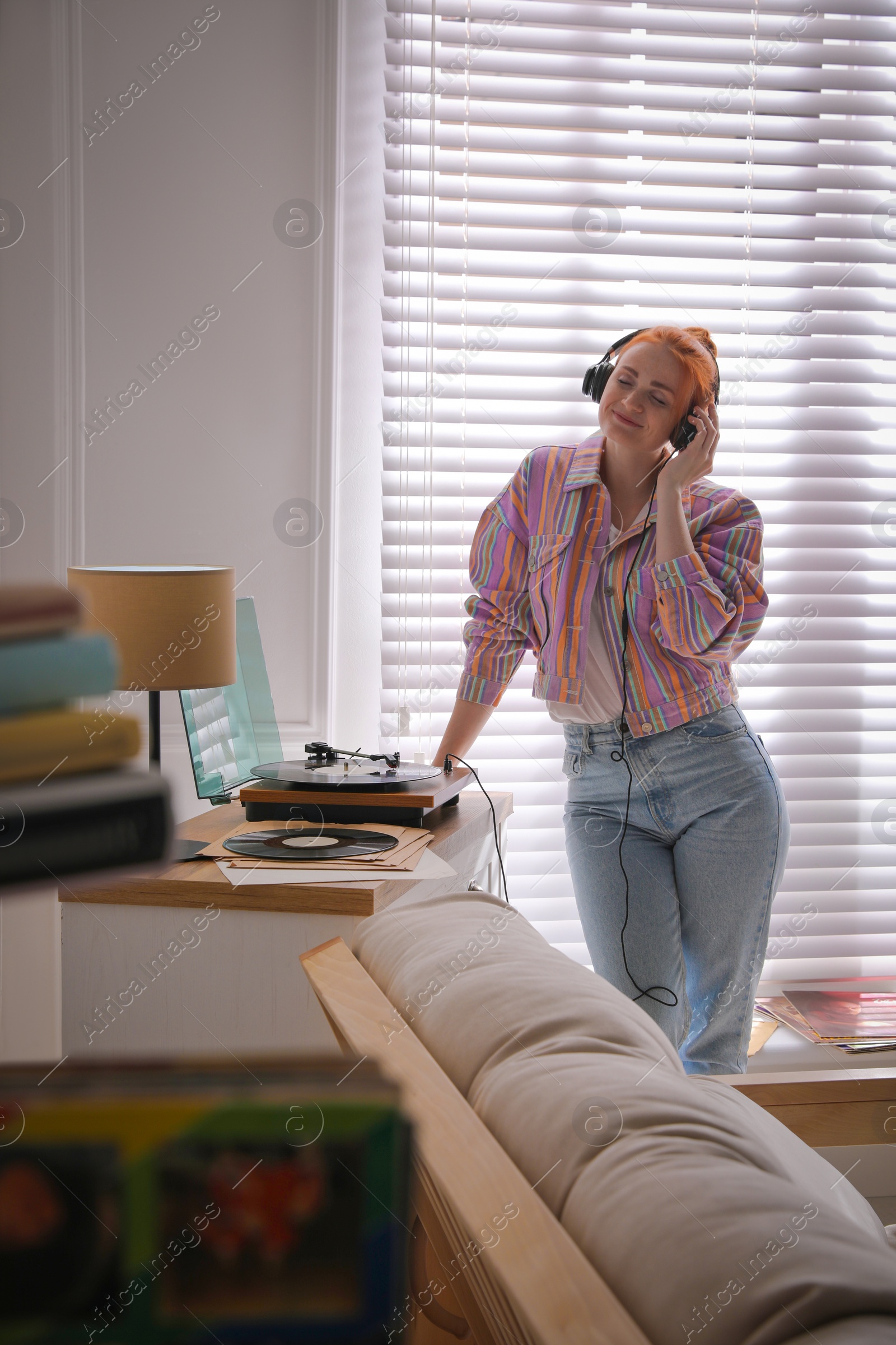 Photo of Young woman listening to music with turntable at home