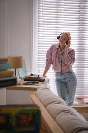 Young woman listening to music with turntable at home