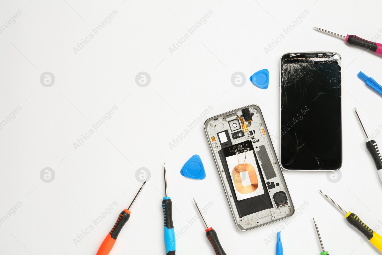 Photo of Damaged smartphone and repair tool set on white background, flat lay. Space for text