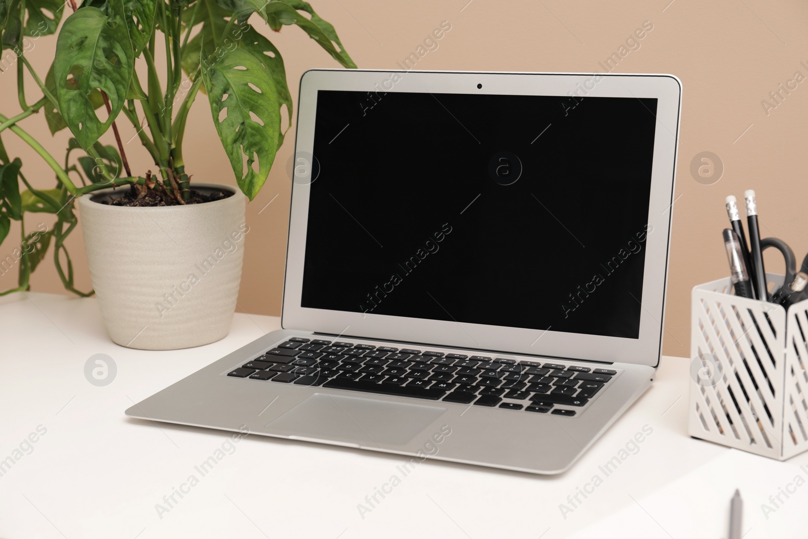 Photo of Cozy workplace with laptop and stationery on desk. Home office