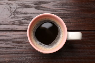 Cup of aromatic coffee on wooden table, top view