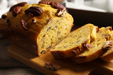 Cut pumpkin bread with pecan nuts on wooden table, closeup