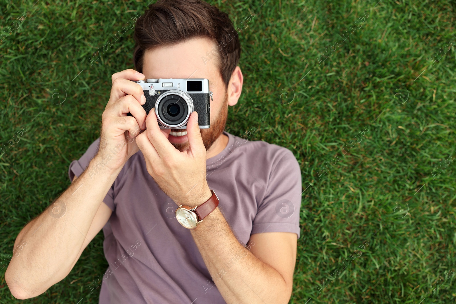 Photo of Man with camera taking photo on green grass, top view. Interesting hobby