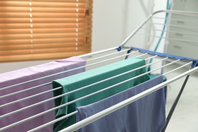 Photo of Clean laundry hanging on drying rack indoors, closeup