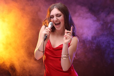 Emotional woman with microphone singing in color lights