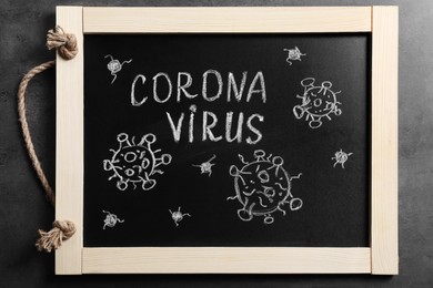 Photo of Blackboard with word Coronavirus on grey table, top view
