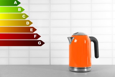 Energy efficiency rating label and electric kettle on grey table