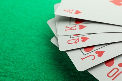Photo of Hand of playing cards on green table, closeup. Space for text