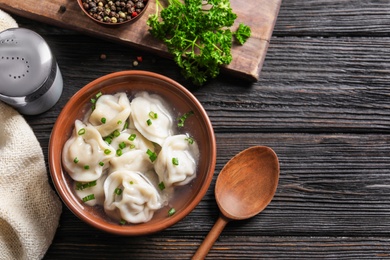 Photo of Bowl of tasty dumplings served on wooden table, flat lay. Space for text