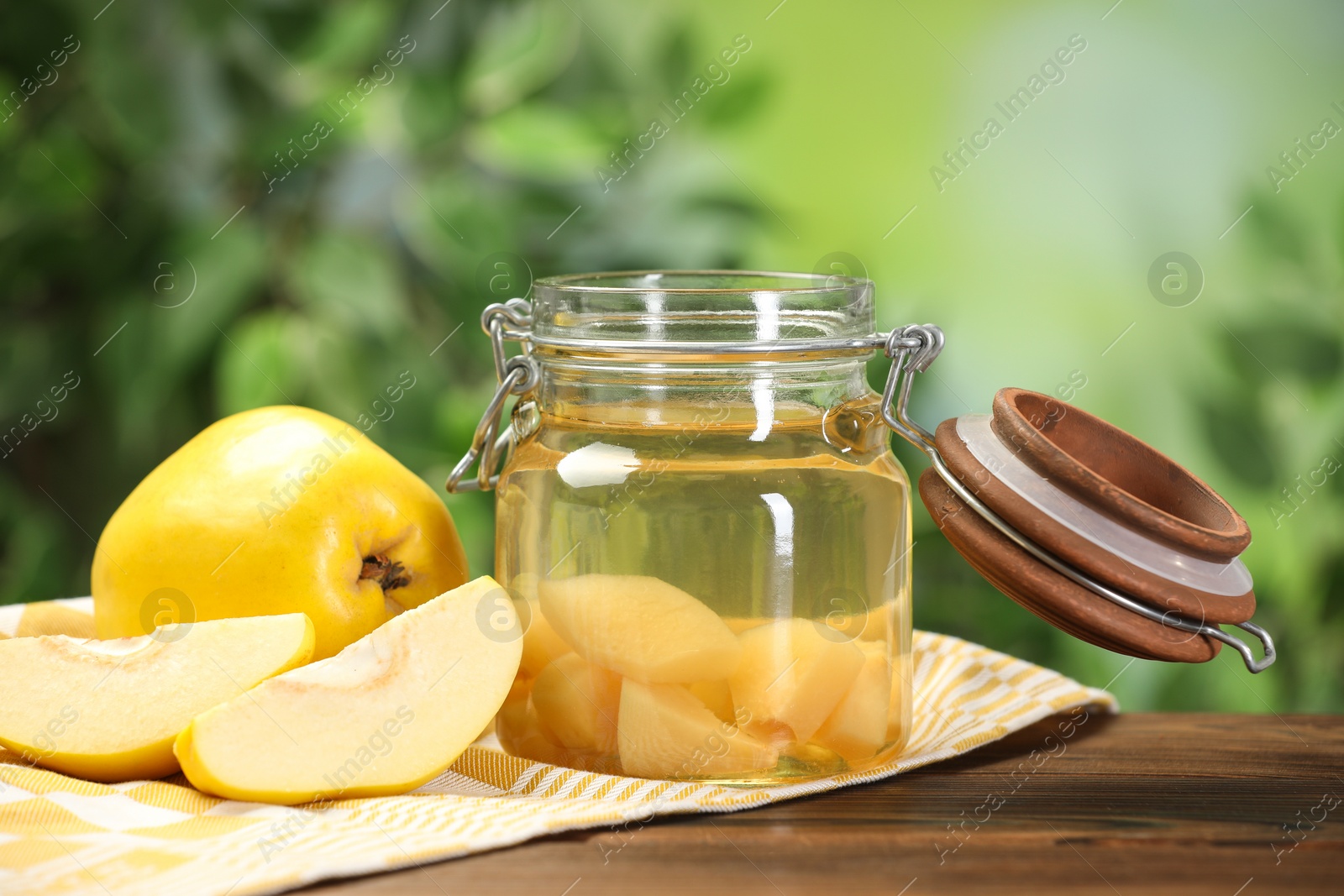 Photo of Delicious quince drink and fresh fruits on wooden table against blurred background