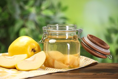 Photo of Delicious quince drink and fresh fruits on wooden table against blurred background