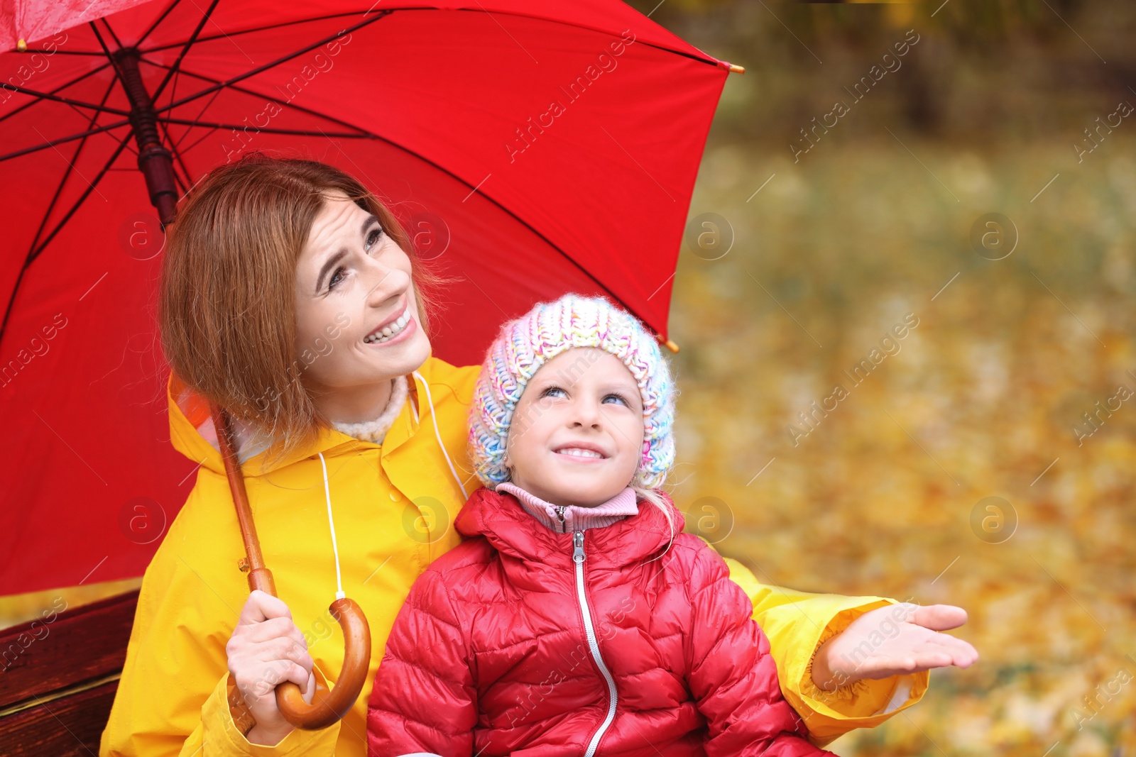 Photo of Mother and daughter with umbrella in autumn park on rainy day