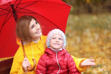 Photo of Mother and daughter with umbrella in autumn park on rainy day