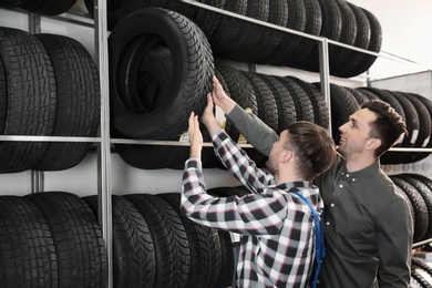 Service center consultant helping customer to choose tire in store