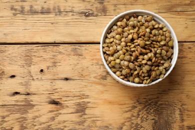 Delicious lentils in bowl on wooden table, top view. Space for text