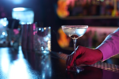 Photo of Bartender with fresh Martini cocktail at bar counter, closeup. Space for text