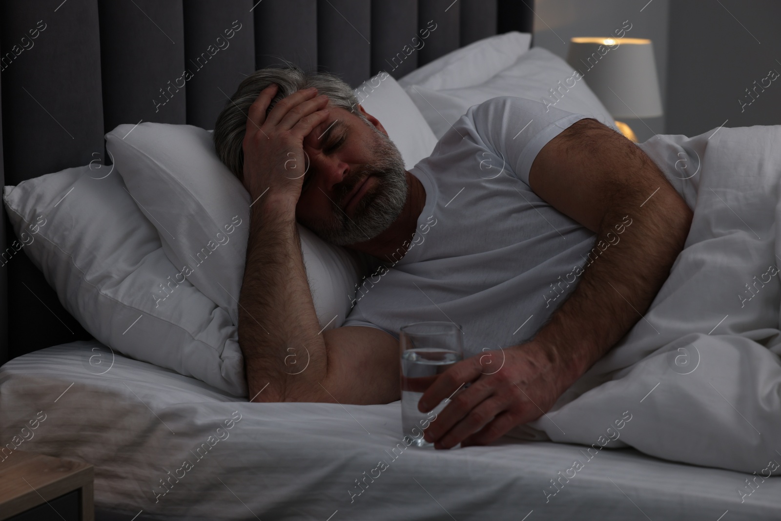 Photo of Mature man suffering from headache in bed at night